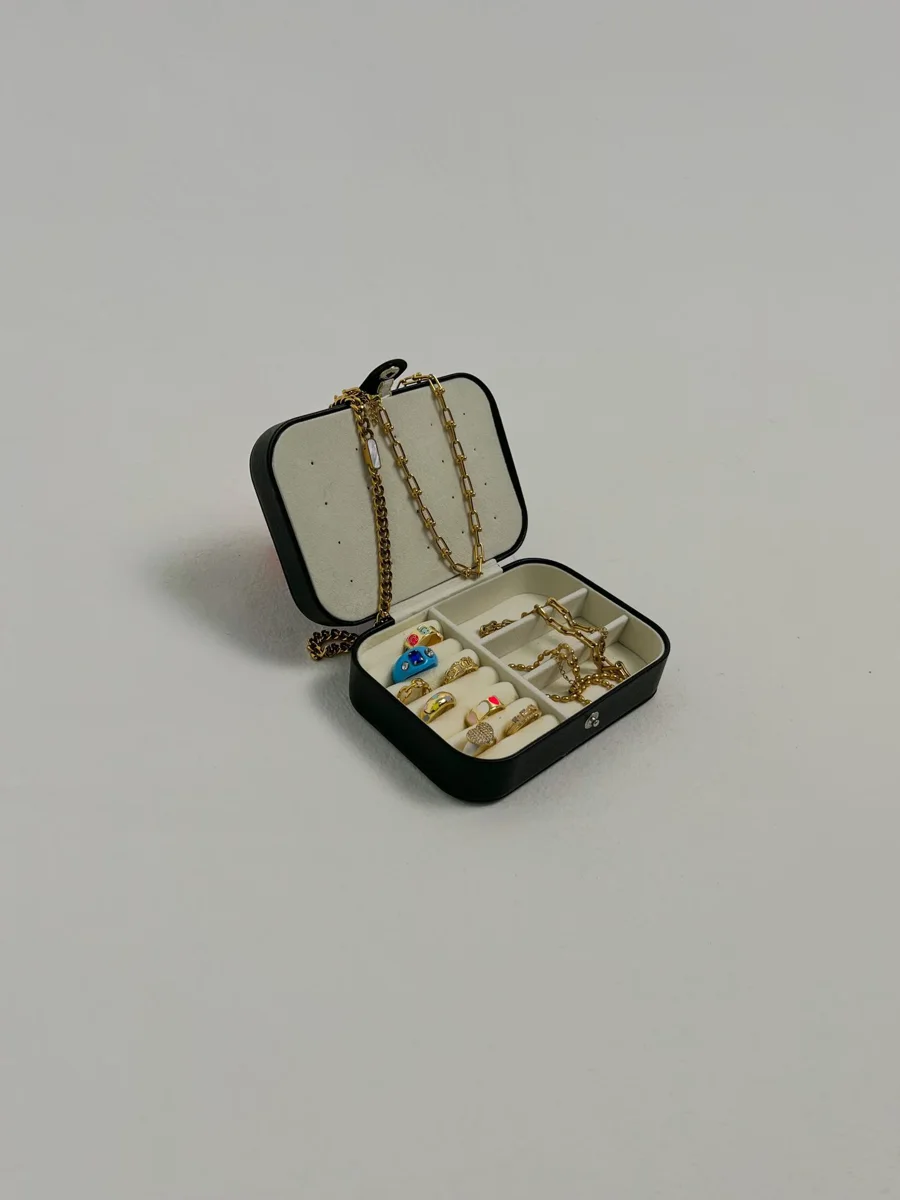 Open black jewellery box containing rings and necklaces.