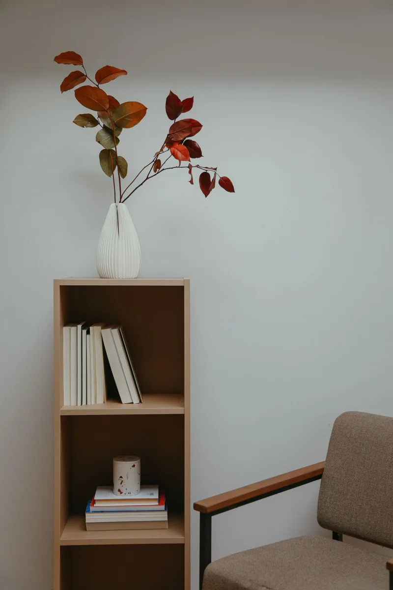 White vase on top of a bookcase.