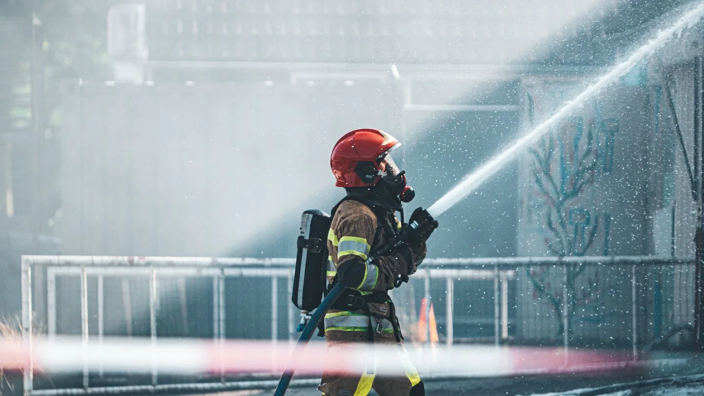 A firefighter using a hose in an outdoor training exercise.