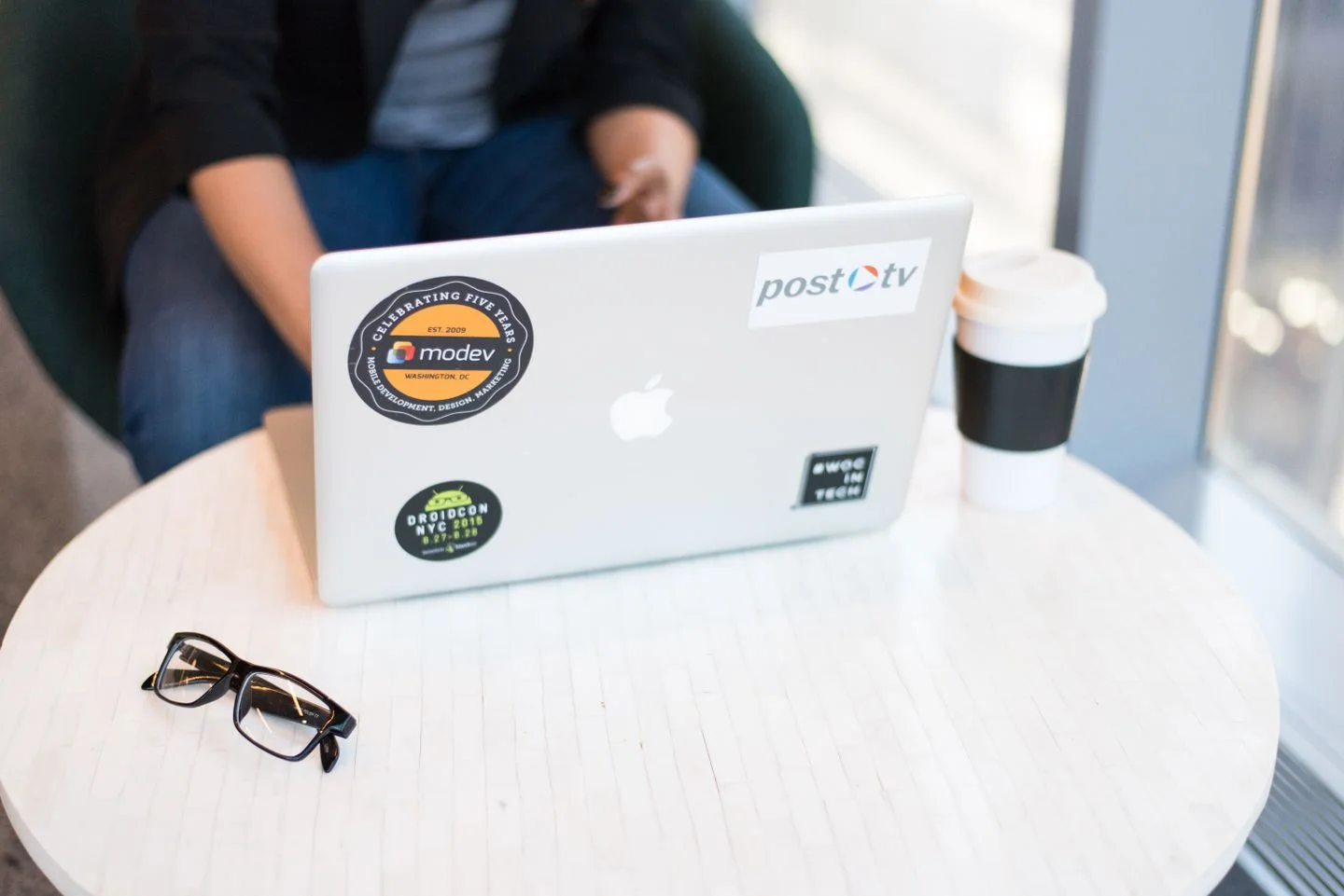 A laptop beside a drinking cup on a table.
