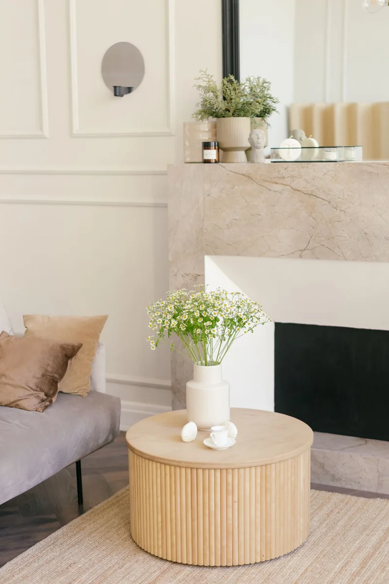 A flower vase on a wooden table beside a sofa.