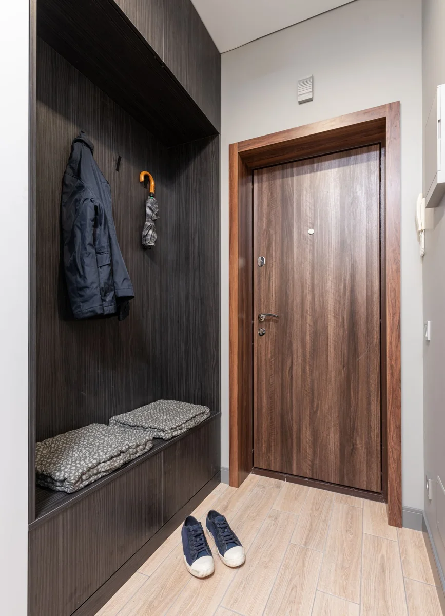 An entrance hall with a door and clothes hanging on hooks