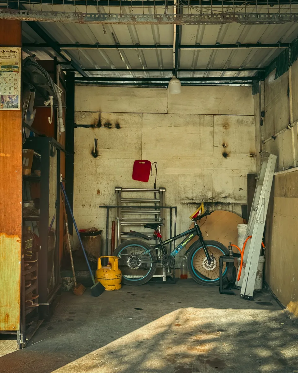 A garage with a bicycle, ladder, shelving and household tools