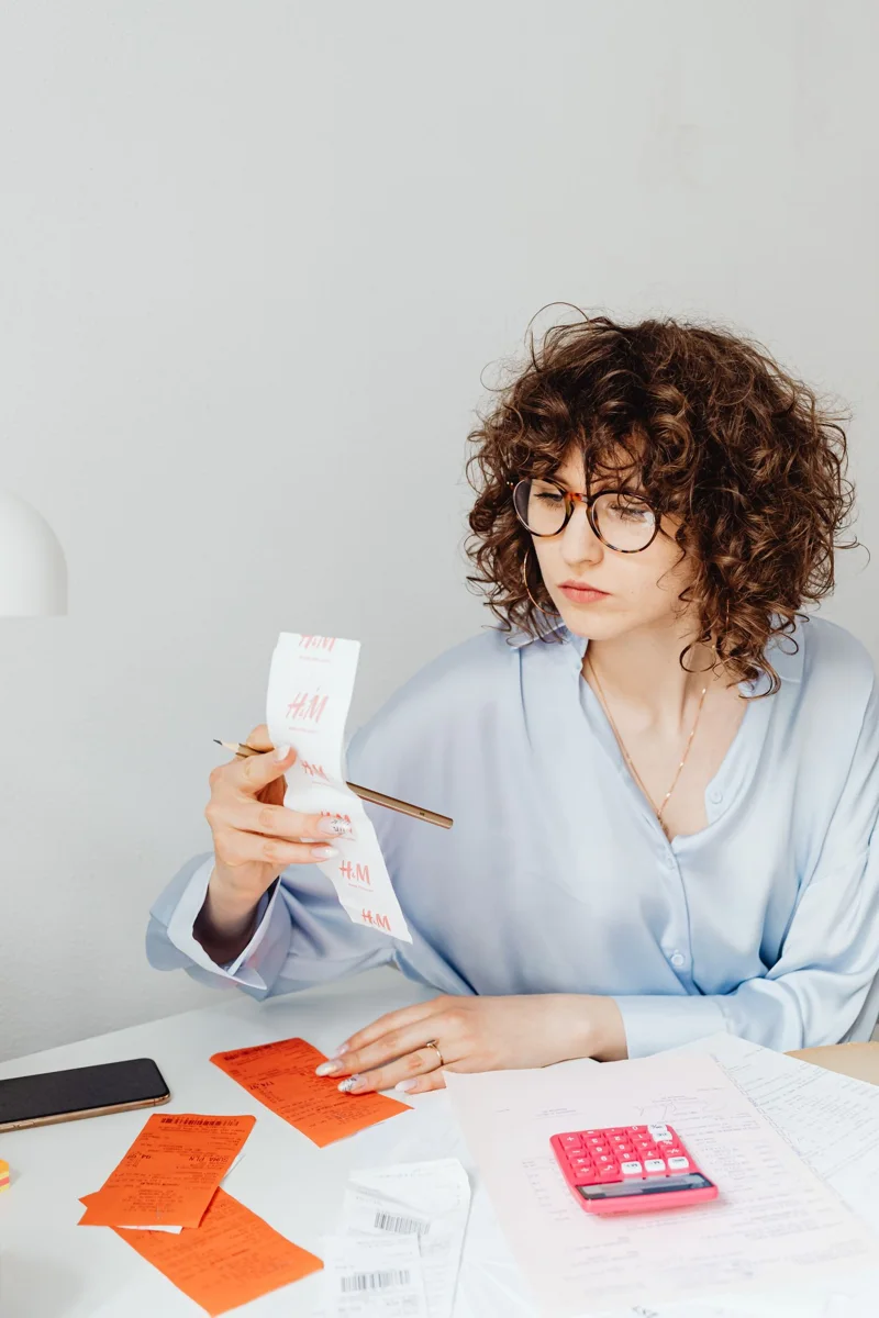 Woman reading a receipt beside a calculator