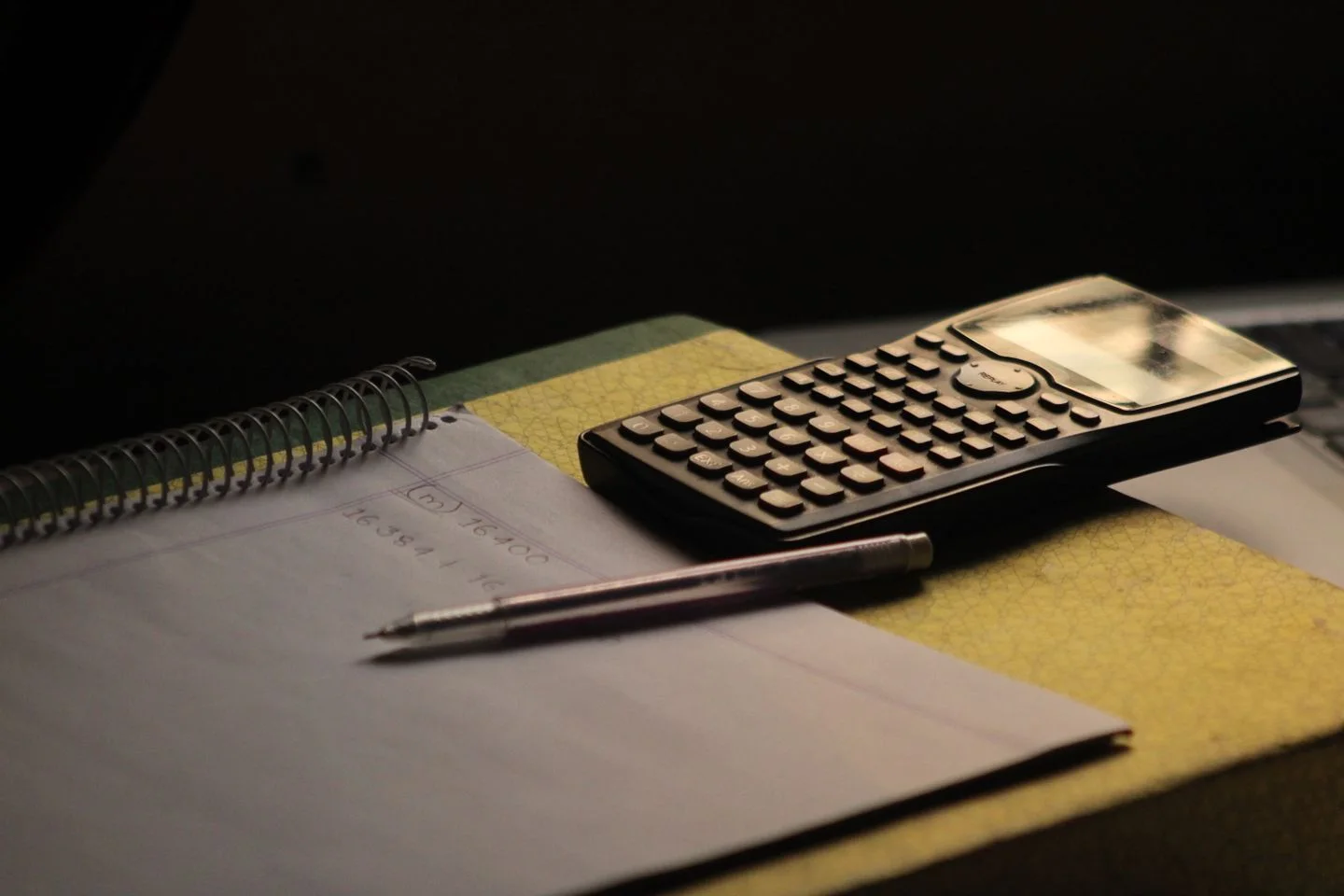 A calculator and notebook on a desk