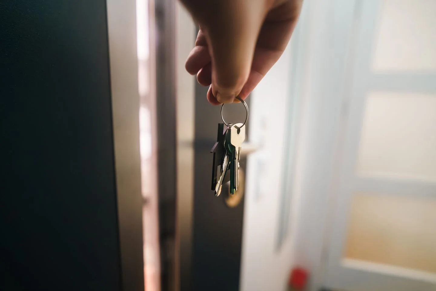 A hand holds keys at a doorway